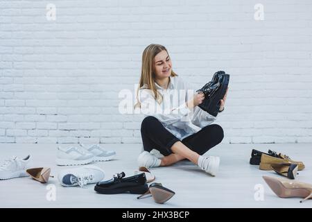 Eleganti scarpe bionda da mentre si siede sul pavimento. Vista laterale di un sacco di scarpe da donna sul pavimento, una scelta di scarpe eleganti. Foto Stock