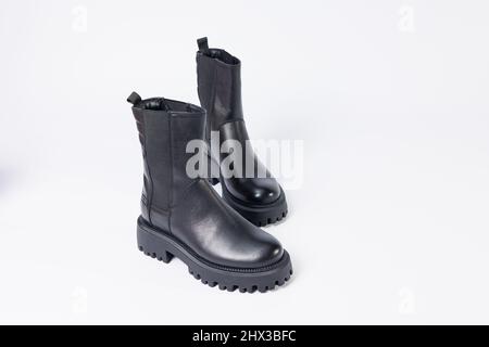 Scarpe da donna su sfondo bianco. Primo piano di stivali chelsea in pelle nera da donna su sfondo bianco. Scarpe per la città. Moda, design e fo Foto Stock