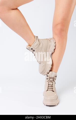 Gambe femminili in pelle beige scarpe della nuova collezione su sfondo bianco gambe femminili in scarpe alla moda in eco-pelle primavera 2022. Foto Stock