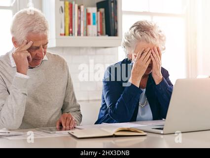 Come faremo a superare tutto questo.... Scatto corto di una coppia anziana che osserva ansioso mentre lavora ad un certo lavoro di ufficio. Foto Stock