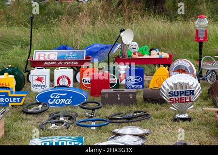 Primo piano di alcuni insegne Vintage per pompe a benzina, lattine di benzina e ruote sterzanti, su uno stand di cimeli automobilistiche al London Classic Car Show 2021 Foto Stock