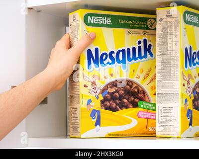 Tambov, Federazione Russa - 19 febbraio 2022 la mano della donna che prende la scatola di cereali Nesquik di cioccolato di Nestle da un armadietto Foto Stock