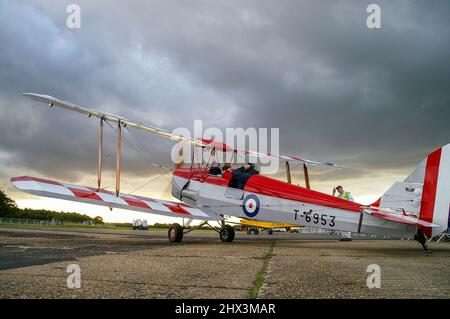 De Havilland D.H. 82A Tiger Moth II biplanare T6953 in attesa di partire dopo uno spettacolo aereo a Dunsfold con pesanti nuvole di tempesta nera in testa. Minaccioso Foto Stock