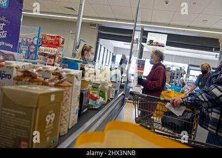 Costo dei generi alimentari viventi al banco check-out Co Op supermarket worker donna che lavora al cliente fino a indossare maschera covid Galles 2022 KATHY DEWITT Foto Stock