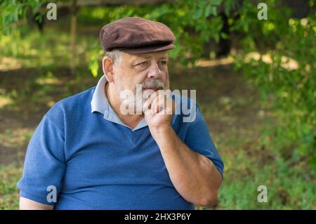 Bel ritratto all'aperto di uomo maggiore caucasico barbuto sotto l'ombra dell'albero Foto Stock