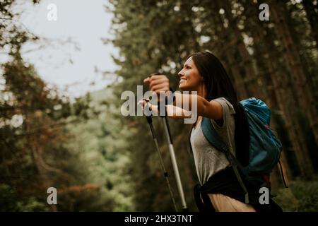 Bella giovane donna zaino in spalla godendo verde bella foresta intorno a lei Foto Stock