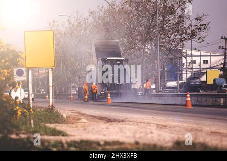 Lavoratori, rullo operativo e di asfalto lastricatore macchina durante la costruzione di strade e lavori di riparazione Foto Stock