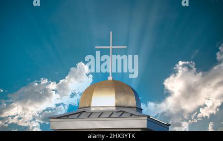 Aganista a croce bianca un cielo blu con strisce chiare sulla sommità della cupola d'oro della chiesa cattolica Foto Stock