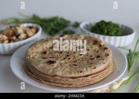 Pane piatto indiano servito con condimento piccante all'aglio verde e cubetti di formaggio casereccio saltato. Scatto su sfondo bianco. Foto Stock