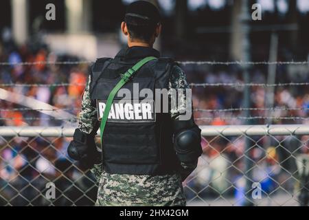 Pakistan soldato in occhiali da sole con la pistola vicino alle Porte principali sul confine Attari Wagah Foto Stock