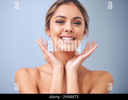 Non poteva essere più felice con il suo regime di cura della pelle. Studio girato di una bella giovane donna su sfondo blu. Foto Stock