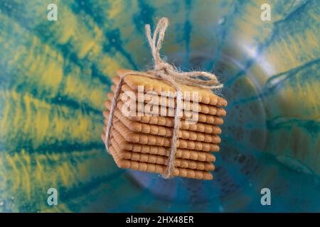 biscotti di burro e legato con un arco di corda di iuta come un presente, levitating su vetro blu translucido, sfondo testurizzato Foto Stock