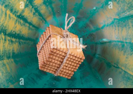 pila di biscotti al burro e legato con un arco di corda di iuta, levitating su sfondo blu testurizzato Foto Stock