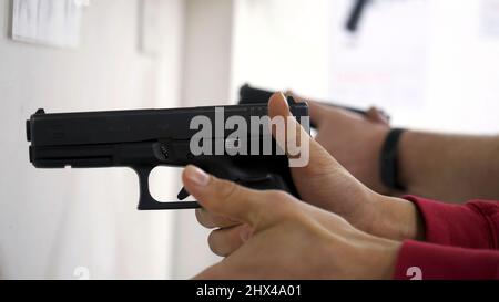 L'istruttore insegna a un uomo di maneggiare un'arma o una pistola. Primo piano delle mani maschili con pistola mentre si allenano con l'istruttore. Primo piano di ricarica manuale g Foto Stock