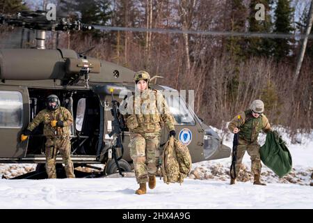 26 febbraio 2022 - Joint base Elmendorf-Richardson, Alaska, USA - U.S. Air Force staff Sgt. Amanda Kopecky, il 773d ingegnere civile Squadron Emergency Management Training non commissionato ufficiale in carica, ritorna da un Alaska Army National Guard UH-60 Blackhawk assegnato al 207th Aviation Regiment durante un esercizio di addestramento sul campo di operazioni congiunte a Camp Mad Bull su Joint base Elmendorf-Richardson, Alaska, 26 febbraio 2022. L'esercizio consisteva in operazioni di sollevamento aereo, costruzione di posizioni di combattimento difensive artiche, e un attacco simulato di armi di piccolo calibro progettato per valutare e strengthe Foto Stock