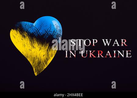 Fermare la guerra in Ucraina. Salva Ucraina. Il cuore è dipinto nei colori della bandiera Ucraina - blu e giallo. Testo stop war, poster in nero Foto Stock