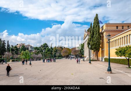 Atene, Grecia - Marzo 6 2022: La gente gode di un pomeriggio soleggiato nel cortile di Zappeio, con l'Acropoli sullo sfondo. Foto Stock