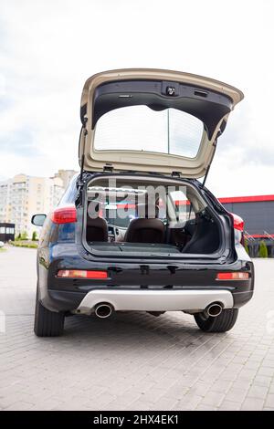 Moderna auto nera, jeep SUV nera su ruote grandi. Vista posteriore del vano bagagli aperto Foto Stock