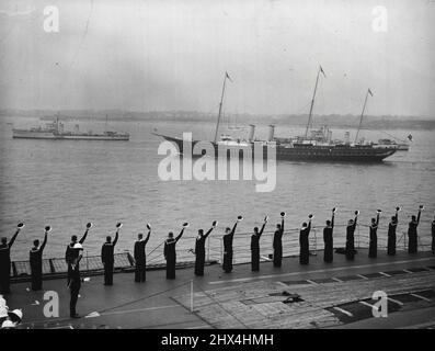 Il re esamina la sua flotta a Spihead - gli uomini del vettore aereo 'glorioso' che acclamano mentre lo yacht reale 'Victoria and Albert' passò le linee. A bordo del Royal yacht 'Victoria and Albert', il re passò attraverso le linee di cinque miglia di 160 navi da guerra e navi mercantili quando fece la sua Coronation Review della Marina britannica e della Marina mercantile a Spihead. Sono state esaminate quasi 300 navi, di cui 17 provenienti da flotte straniere. Maggio 20, 1937. Foto Stock