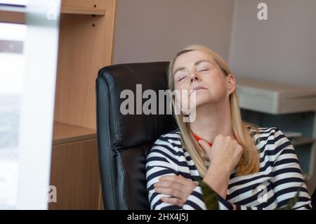 Donna che riposa in ufficio. Donna addormentata in una sedia da ufficio Foto Stock