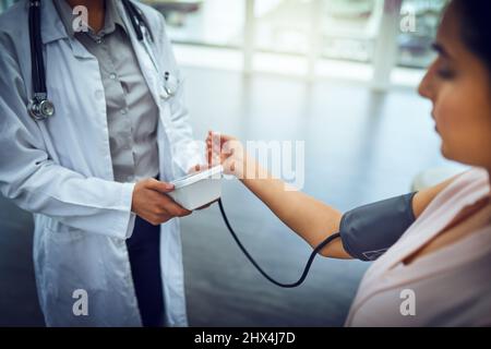 I controlli della pressione sanguigna sono tutti parte di un controllo di routine. Primo piano di un medico che controlla la pressione sanguigna di un paziente. Foto Stock