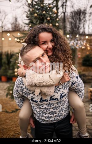 giovane coppia che cammina nel giardino di natale vicino all'albero di natale Foto Stock