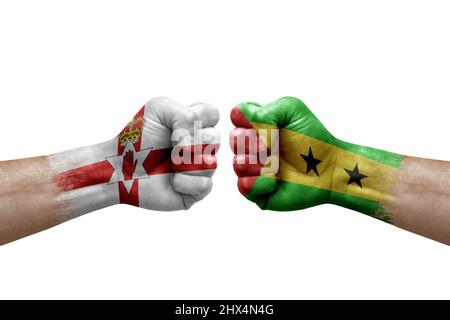 Due mani si pugno l'una all'altra su sfondo bianco. Bandiere di paese dipinte fists, concetto di crisi di conflitto tra l'irlanda del Nord e sao tomé e pri Foto Stock