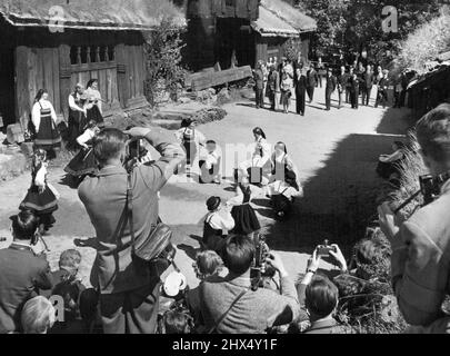 Visita reale in Norvegia -- un gruppo di bambini piccoli ***** Costumi della valle di Setes facendo un ***** Danzare nel cortile delle case coloniche del Medioevo al Museo Folcloristico Norvegese in onore della Regina. (Visto in background con il suo entourage. Il 24th giugno la Regina Elisabetta II e il Duca di Edimburgo arrivarono ad Oslo in una visita statale di 3 giorni in Norvegia. Questa è la prima visita della Regina in qualsiasi paese al di fuori del Commonwealth britannico. Il secondo giorno della visita includeva una festa in giardino presso l'Ambasciata britannica e uno spettacolo reale di Galla al Teatro Nazionale in serata. Giugno 25, 1955. Foto Stock