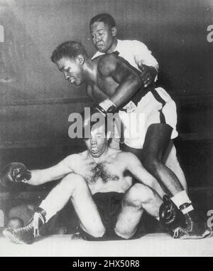 Paddy Hits the Deck -- Paddy De Marco, Brooklyn leggero, è uomo basso sul totem palo come egli è galleggiato da Arthur King di Toronto nel quarto round del loro dieci-rounder a Brooklyn Eastern Parkway Arena qui stasera. L'arbitro Jimmy Freeman raggiunge la fine di tenere King, che quasi inciampa sul suo nemico caduto. Re, pretendente del titolo leggero dell'Impero britannico, ha vinto una vittoria sconvolta con decisione unanime sul favorito De Marco. Maggio 26, 1952. (Foto di AP Wirephoto). Foto Stock