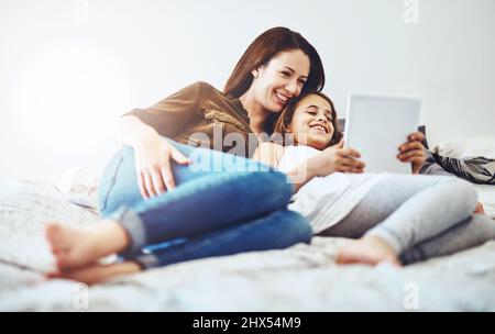 Trovare cose divertenti da fare online. Scatto di una bambina e di sua madre usando un tablet digitale insieme. Foto Stock