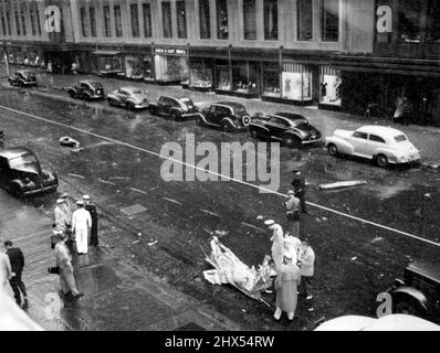 Esaminare il relitto dell'aereo -- gli spettatori su 34th strada esaminare il relitto dell'aereo che si è schiantato nel palazzo dell'Empire state a New York, luglio 28. L'aeroplano era diretto all'Aeroporto di Newark quando si schiantò nei piani superiori della struttura. Luglio 28, 1945. (Foto di stampa associata). Foto Stock