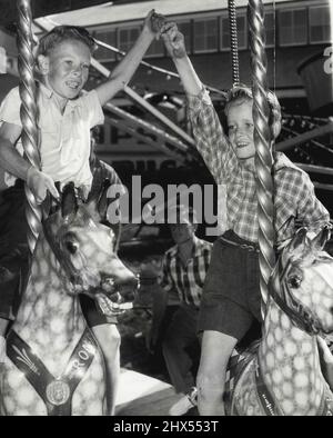 Il divertimento della fiera arriva a Sydney una volta all'anno per i fratelli Bankstown Maurice, 11 (a destra) e Brian McInerney, 8. Ma scene come queste sono prezzi giornalieri per le famiglie che corrono la coda di side-show sopra l'Australia. Aprile 04, 1955. Foto Stock