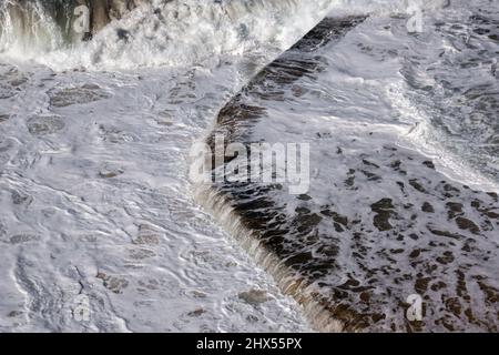 Le onde di marea dell'Oceano Atlantico si rivivgono sul bordo di una piscina di acqua salata sul litorale di Sintra in Portogallo Foto Stock