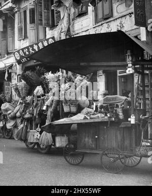 A Singapore. Le ruote sono usate come mezzo per trasportare ogni genere di cose in Malaya. Qui sono mostrati un venditore in viaggio di spazzole, scope scope fruste e tutti i tipi di requisiti domestici con sulla destra un portatile lato marciapiede ristorante. Dicembre 29, 1955. (Foto di Ross/Fairfax Media) Foto Stock