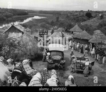 Village Arrival......in questa scena dal 'Mogambo' di M-G-M, girato in Africa, Clark Gable e i membri della sua festa safari sono appena arrivati in un piccolo villaggio nativo. Gable, pistola trasportante, stenos in primo piano, come Donald Sinden, membro del suo partito, fa la sua fotografia. AVA Gardner sta per uscire dal veicolo a sinistra.John Ford ha diretto il film Technicolor con Sam Zimbalist produzione. Ottobre 31, 1953. Foto Stock