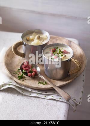 Due tazze piccole di zuppa di vongole del New England, cucchiaio contenente un po' di pancetta, sul vassoio da portata Foto Stock