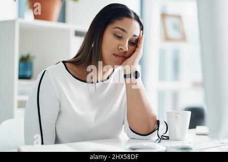 Questo lavoro è davvero un foro. Scatto di una giovane donna d'affari che guarda annoiata mentre si siede ad una scrivania in un ufficio. Foto Stock