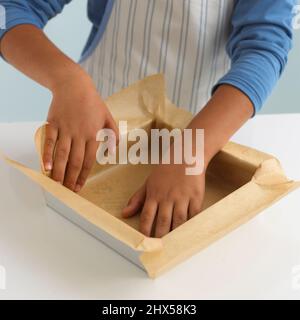 Teglia per torte quadrata con fodera per ragazzo e carta oleata, primo piano Foto Stock