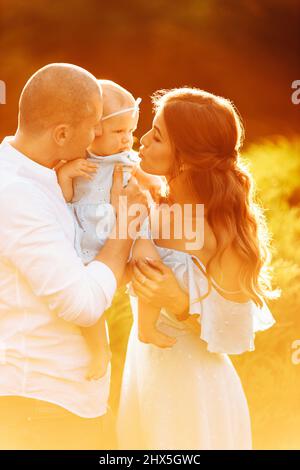 Bella mamma e papà con bella figlia al parco, i giovani genitori tenere carina bambina in braccia teneri, sorriso, godersi i momenti felici della famiglia Foto Stock