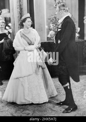 La Regina all'Opera. La regina sorridente, raggiante in una bella abito da sera e magnifici gioielli visto chiacchierare con il primo ministro Sir Anthony Eden, indossando l'abito di un cavaliere delle Garters nell'atrio della Royal Opera House, Covent Garden, la notte scorsa. L'ultima notte della loro visita di Stato di tre giorni in questo paese, il presidente del Portogallo, il generale Craveiro Lopes, e sua moglie, hanno visitato Covent Garden dove hanno visto l'opera "la sposa barrata" come ospiti di S.M. la Regina e la Famiglia reale. Ottobre 28, 1955. (Foto di Fox Photos). Foto Stock