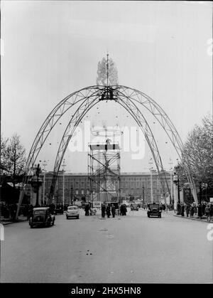 Il centro commerciale ottiene che il look di Coronation -- Con la folla radunata sui marciapiedi e con Buckingham Palace come backcloth, i lavoratori si alzano in posizione una replica della corona di una principessa, che pende da un arco di 65 piedi - uno dei quattro per essere parte della decorazione di incoronazione nel Mall, Londra. A cima dell'arco sono un leone e un unicorno, in tubi d'acciaio. La coronetta è stata sollevata in posizione al giorno (sabato). Maggio 16, 1953. (Foto di Reuterphoto). Foto Stock