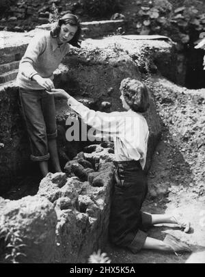 Gli studenti americani cercano Londra romana -- esaminando una ricerca sul sito bombardato al giorno sono, a sinistra, la signorina Marianne Moore, di Washington, e la signorina Charlotte Fitzpatrick di St. Paul. Gli studenti archeologici americani, qui alla ricerca di resti romani a Londra e in altre città romane, hanno iniziato i lavori questa mattina (martedì) su un sito bombardato a King's Head Yard, Borough High Street, Southwark, Londra. Luglio 30, 1946. (Foto di Reuterphotos). Foto Stock