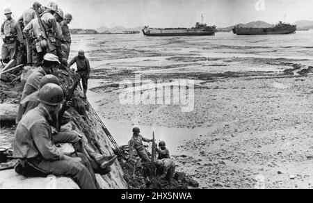 In attesa di alta marea -- Marines sul muro di mare Inchon guardare compagni chiaro fango-marooned sbarco fase dopo basse maree aveva lasciato LST in background alto e asciutto. L'acqua scende a 30 piedi a questo punto, rendendo impossibile le operazioni di atterraggio a bassa marea. Settembre 22, 1950. (Foto di AP Wirephoto). Foto Stock