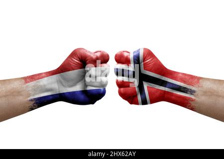 Due mani si pugno l'una all'altra su sfondo bianco. Bandiere di paese dipinte pugni, conflitto concetto di crisi tra i paesi bassi e norvegia Foto Stock