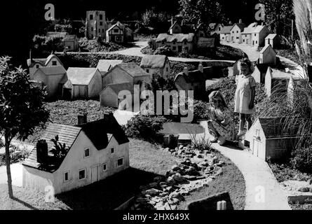 Fairyland in miniatura -- Villaggio del suo proprio - Janice (inginocchiato), introduce la sua piccola amica Pamela Lawton al suo villaggio. Janice Palmer, di Southampton, di quattro anni, ha una propria fairyland in fondo al suo giardino. Suo padre ha costruito per lei un villaggio inglese in miniatura, in un ambiente delizioso a poche centinaia di metri dal trambusto e il trambusto del traffico principale-letto. Il sig. Palmer, un camionista, ha speso più di un anno che costruisce il villaggio che vanta una chiesa, smithy, villaggio Foto Stock