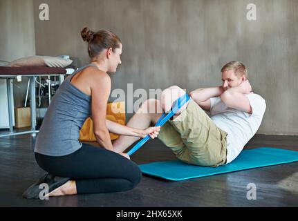 Shell lo riporta a 100. Shot di una fisioterapista femminile che ha una sessione con un amputee maschio giovane. Foto Stock