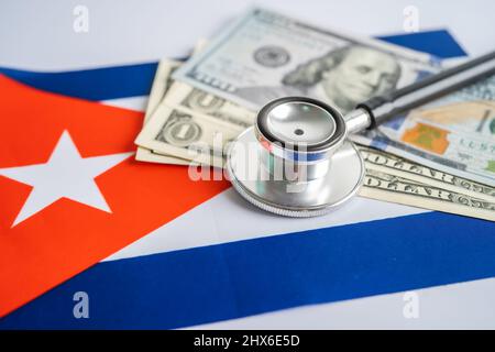 Stetoscopio nero con banconote in dollari USA sul fondo della bandiera di Cuba, concetto di Business e Finanza. Foto Stock