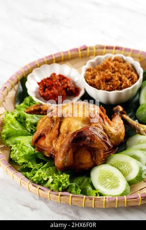 Ayam Ingkung Goreng o Bakakak Hayam, pollo intero fritto profondo, ricetta tradizionale indonesiana, di solito servita con Sambal e verdure Foto Stock