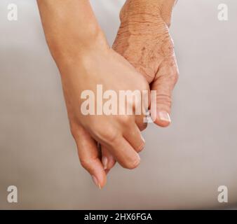 Tenendolo fino alla fine, si è scattato un colpo di giovane donna e di anziana donna che tiene le mani. Foto Stock