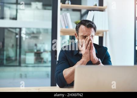 Spero di non aver perso quel cliente. Shot di un uomo d'affari maturo che guarda stressato fuori alla sua scrivania. Foto Stock